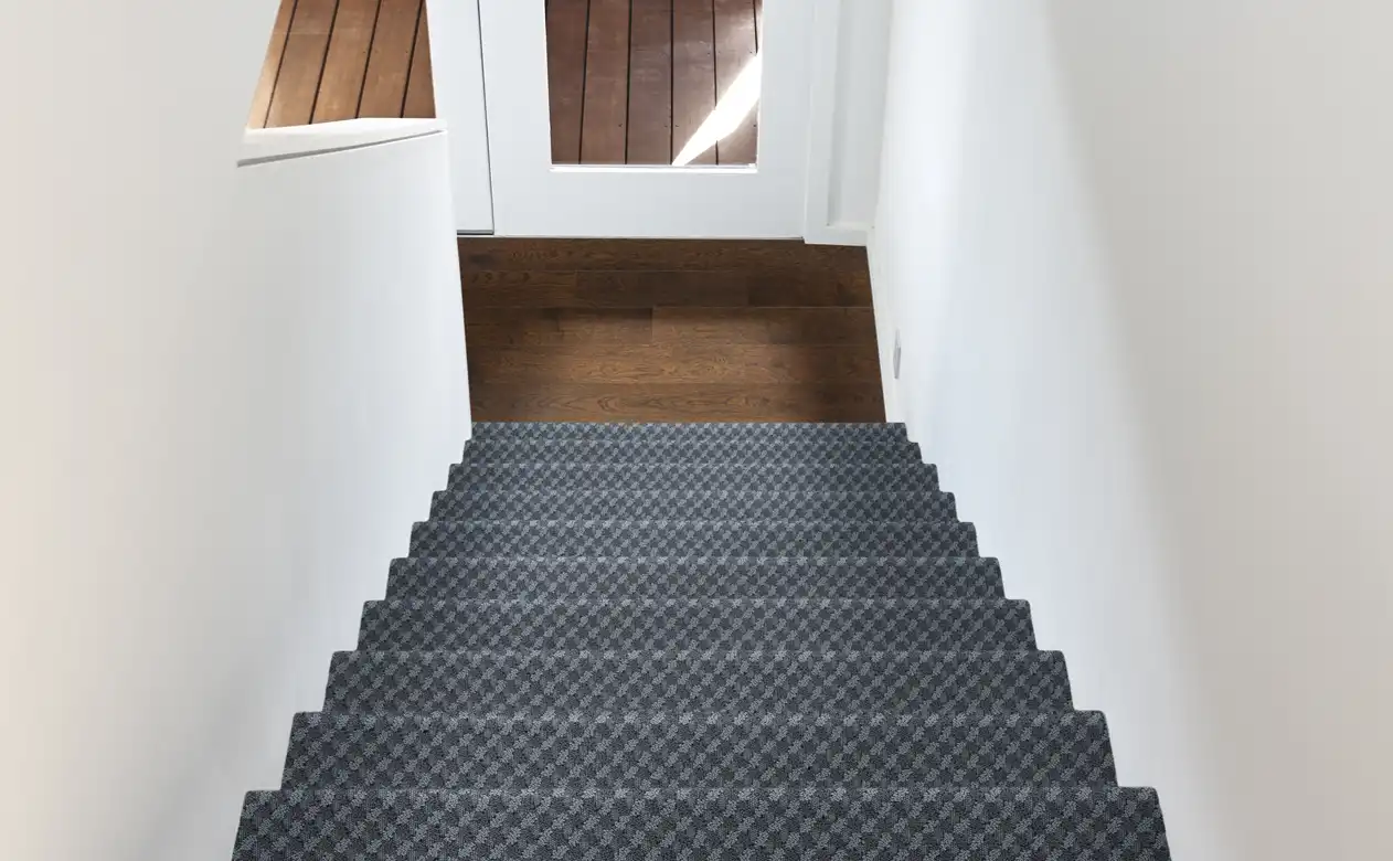 Grey carpeted stair runner over hardwood. 